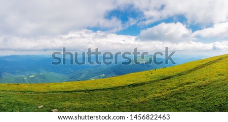 beautiful panorama of a summer landscape. grassy hills and distant ridges, amazing scenery in mountains. sunny weather with cloudy sky on a windy day. picturesque view in to the horizon