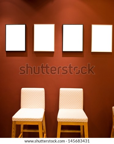 Group of picture frames on red wall.