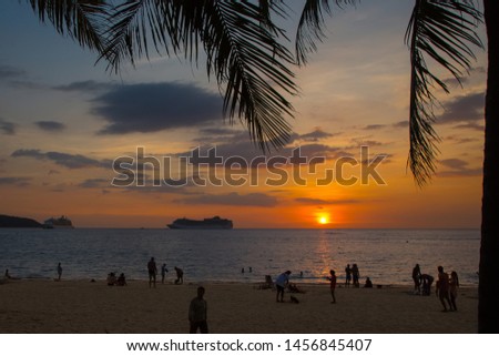 Silhouette of a cruise ship on the background of the sea sunset. Cruise ship anchored at Patong beach in Phuket Island, Thailand. Silhouettes of people at sunset. Skydiver flying behind the boat.