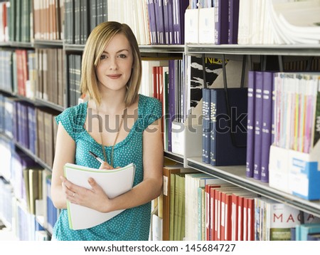 Portrait of a female college student standing in the library Royalty-Free Stock Photo #145684727