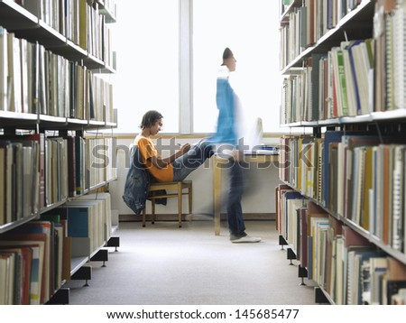 Side view of a young male college student doing homework in the library Royalty-Free Stock Photo #145685477
