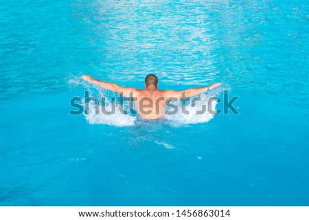 Male swimmer performing the butterfly stroke at outdoor swimming pool