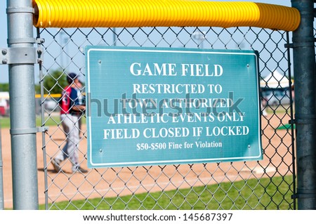 A sign posted on a baseball field stating a restriction violation.