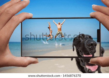 Woman photographing on cell phone happy couple on the beach and dog.