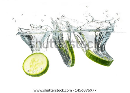 Sliced cucumber splashing water isolated on white background. Skin moisturizing cosmetics concept