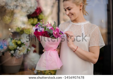 Girl holding a bouquet of crimson orchid and violet hyacinth decorated with green leaves wrapped in rose color paper