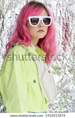 woman with pink hair in glasses on foil background