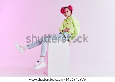 woman in a green jacket with pink hair sitting