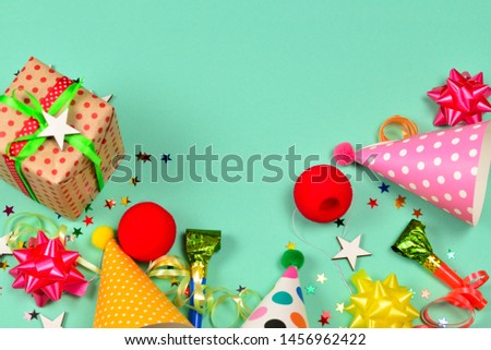 Birthday caps,  present, confetti, ribbons,  stars,  clown noses on a green background. Space for text or design.