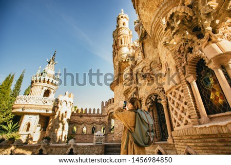 Female backpacker photographing Castillo de Colomares Benalmadena, Malaga, Spain while sightseeing on her summer vacation using a smartphone