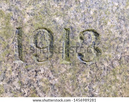 The year 1913 carved in granite, painted in black and covered with green lichen – a detail of an inscription produced that year