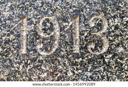 The year 1913 carved in granite, covered with yellow lichen – a detail of an inscription produced that year