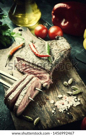 Grilled beef steak on wooden board. Hot meet with vegetables and spices. Retro stylization, vintage film filter