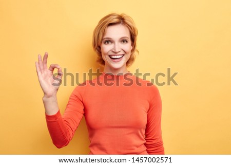 Close up portrait of attractive happy excited blonde woman with beaming smile,showing ok gesture, everything is ok, no problem, agreement concept. body language