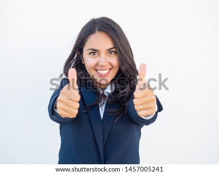 Smiling positive professional showing thumbs up with both hands. Happy beautiful young Latin woman in office suit making like gesture. Success concept