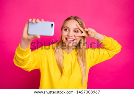 Photo of pretty lady making selfies showing v-sign near eye wear yellow hoodie isolated pink background