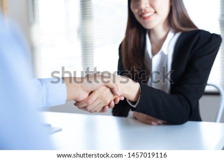 Asian young businesswoman smiling handshake with businessman partner making agreement business together in the work office