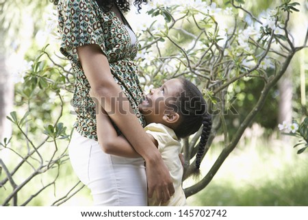 Side view of happy girl hugging mother in garden