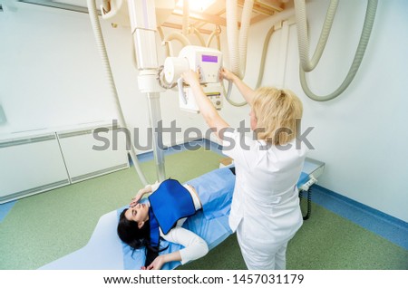 Radiologist and patient in a x-ray room. Classic ceiling-mounted x-ray system. Medical equipment