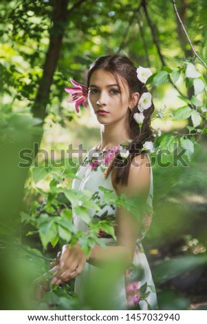 beautiful girl with lilies in her hair, flowers in the luxurious dark hair of a young lady