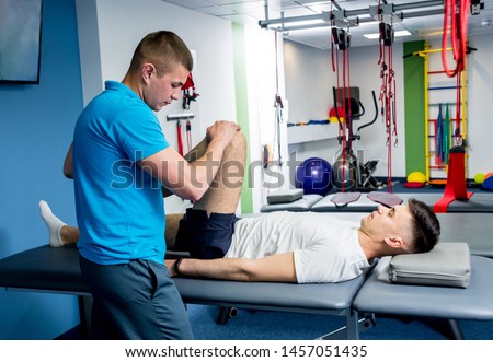 Rehabilitation therapy. Physiotherapist working with young male patient in the rehabilitation center. Treatment pain in spine Royalty-Free Stock Photo #1457051435