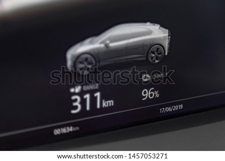 Close up shot of fully electric car dashboard trip computer display showing the status of the battery and available range in kilometers Royalty-Free Stock Photo #1457053271