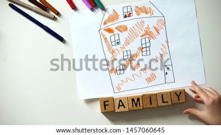 Family word made of cubes lying near kids house drawing, orphan and charity