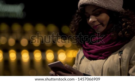 Lady watching photos on her smartphone and smiling, nice romantic memories