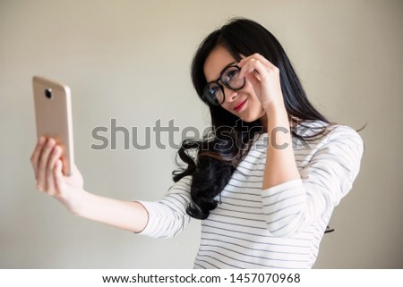 High fashion look. Casual stylish Asian beautiful young woman model with glasses, red lips, hipster strip cloth selfie by smartphone. Hipster or Bohemian female lifestyle with copy space for text.