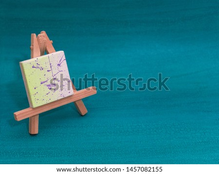 Wood easels or art work boards with painted canvas over turquoise background with copy space 
