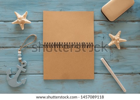Top view of note book, starfishes, anchor, pen on a blue wooden background. Summer concept, Travel concept.  