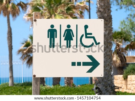 sign in the toilet against the palm trees in the Israeli Park