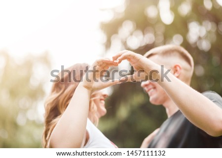 Beautiful Couple In Love Making Heart With Hands. Couple embracing and kissing outdoors. Romantic Relationships