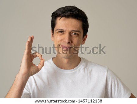 Close up portrait of young caucasian man smiling and doing OK sign. Feeling confident and satisfied. Isolated on neutral background. People, positive human facial expressions and emotions concept.