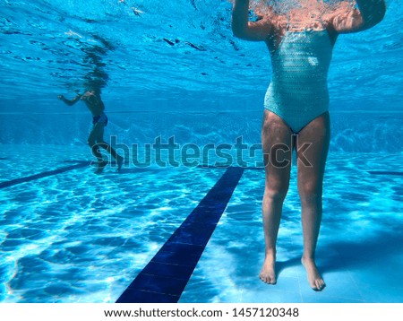 Young girl dives into a pool in a summer day. Underwater view 