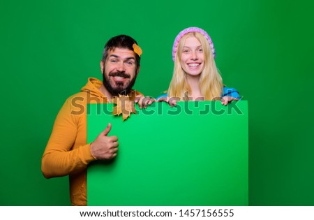 Season sales, autumn holiday. Happy couple in sport wear holds blank banner. Autumn couple advertise product. Advertisement. Happy couple in seasonal clothes with golden leafs. Casual autumn clothes.