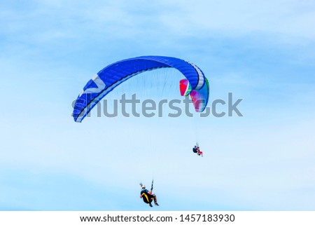 Two paragliders flies over the clean blue sky