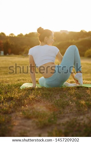 Magnificent young woman relaxing in nature and doing yoga in rays of sun