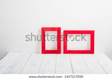 pair of empty red picture frames on white wooden table
