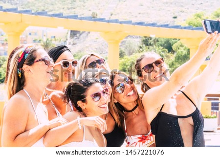People women friends have fun together smiling and laughing taking a selfie picture with a smart phone all together - concept of friends and summer with joyful and hapiness for ladies