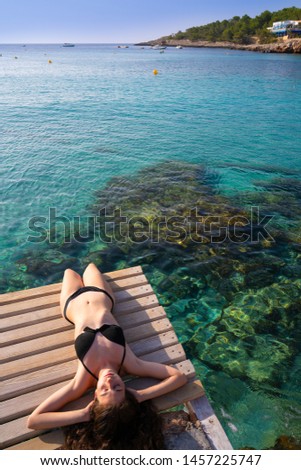 Ibiza bikini girl relaxed at Portinatx beach  pier in Balearic Islands