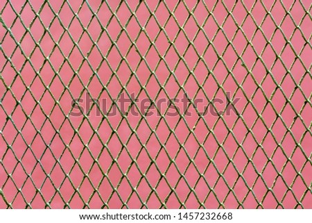 Image of metal grid on pink wall background for use as abstract background.