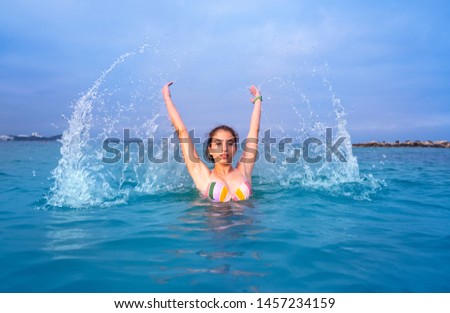 Young woman girl water splash in Ibiza beach of Santa Eulalia at Balearic Islands