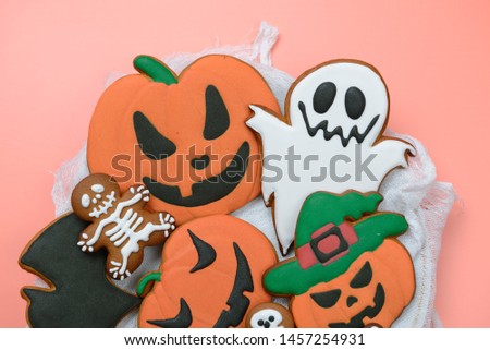 The hand-made eatable gingerbread Halloween pumpkin, ghosts, bat and sceletons on pink background