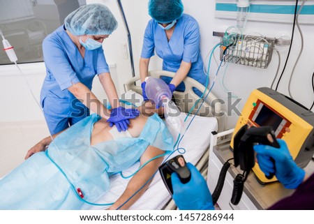 Doctors give resuscitation to a male patient in the emergency room. Cardiac massage. Defibrillation Royalty-Free Stock Photo #1457286944