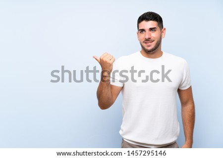 Caucasian handsome man over isolated blue background pointing to the side to present a product