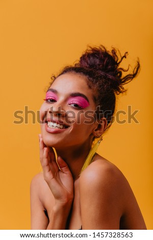 Close-up shot of gorgeous african woman with sincere smile. Indoor portrait of winsome black girl with pink makeup.