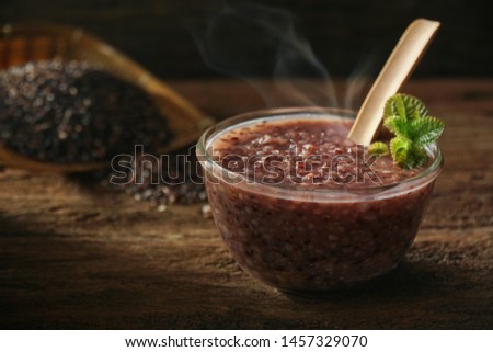 Close up of boiled rice berry in bowl on wooden table. Rice berry on background. Food and healthy concept.
