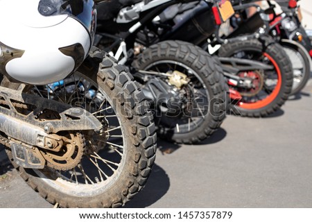 Rear tires on a row of motocross dirt bikes, in a motorcycle riding concept with space for text on the right 