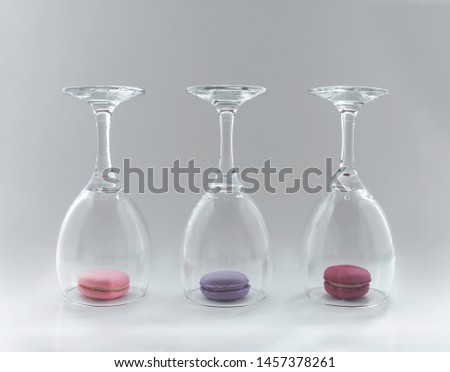 Traditional French colorful, crunchy macarons in wine glasses on light grey background
